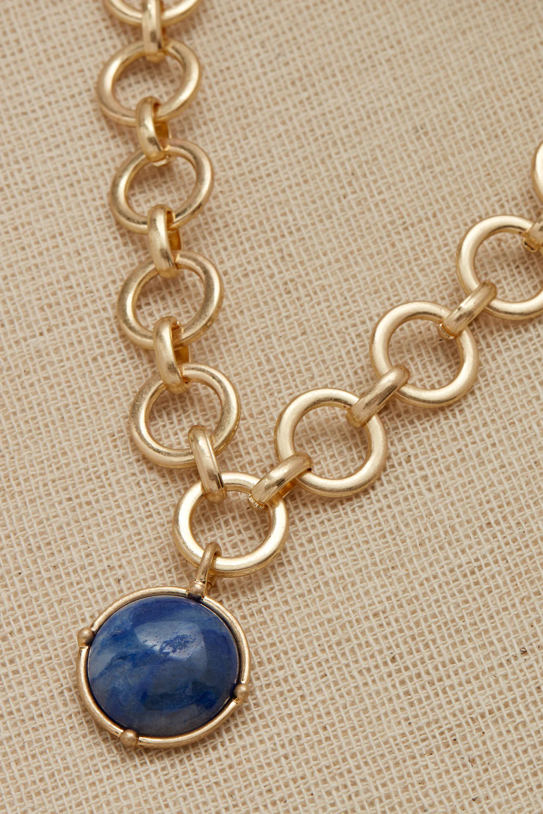 Short gold circular link necklace with a round blue semi precious pendant