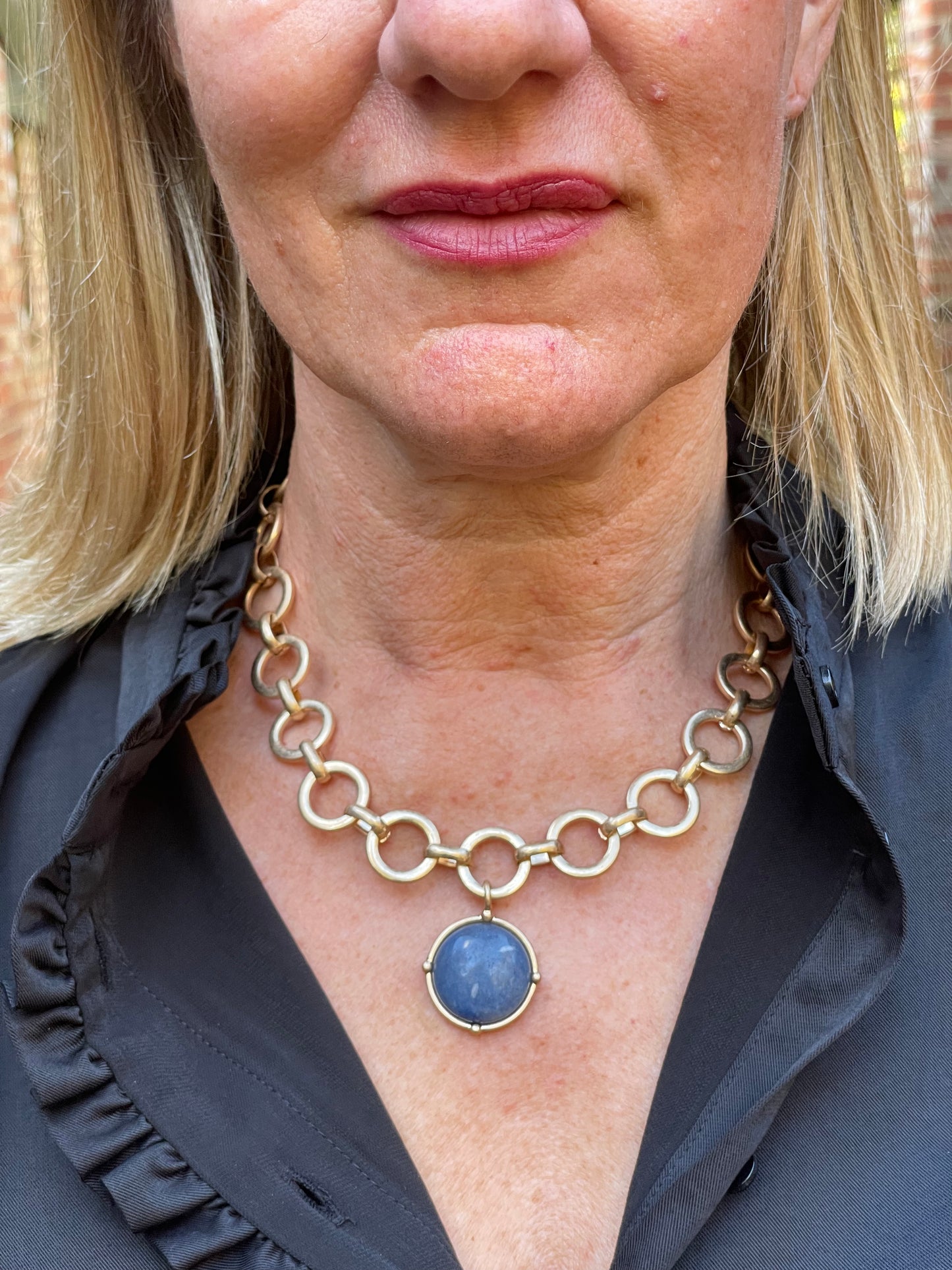 Short gold circular link necklace with a round blue semi precious pendant